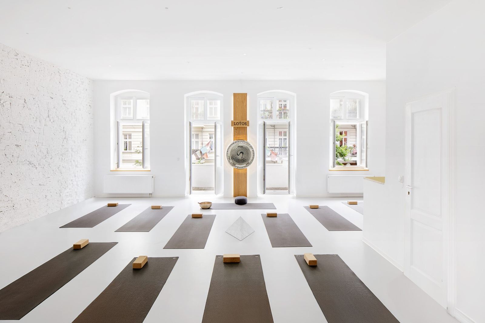 Rows of dark mats in a white studio under arched windows